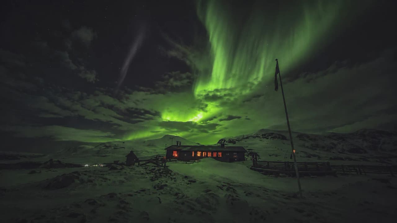 Un refuge lumineux sous des aurores boréales éclatantes en Laponie suédoise.