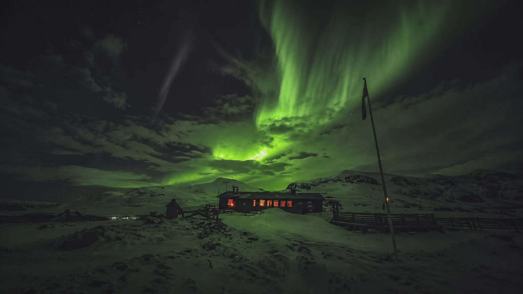 Un refuge lumineux sous des aurores boréales éclatantes en Laponie suédoise.
