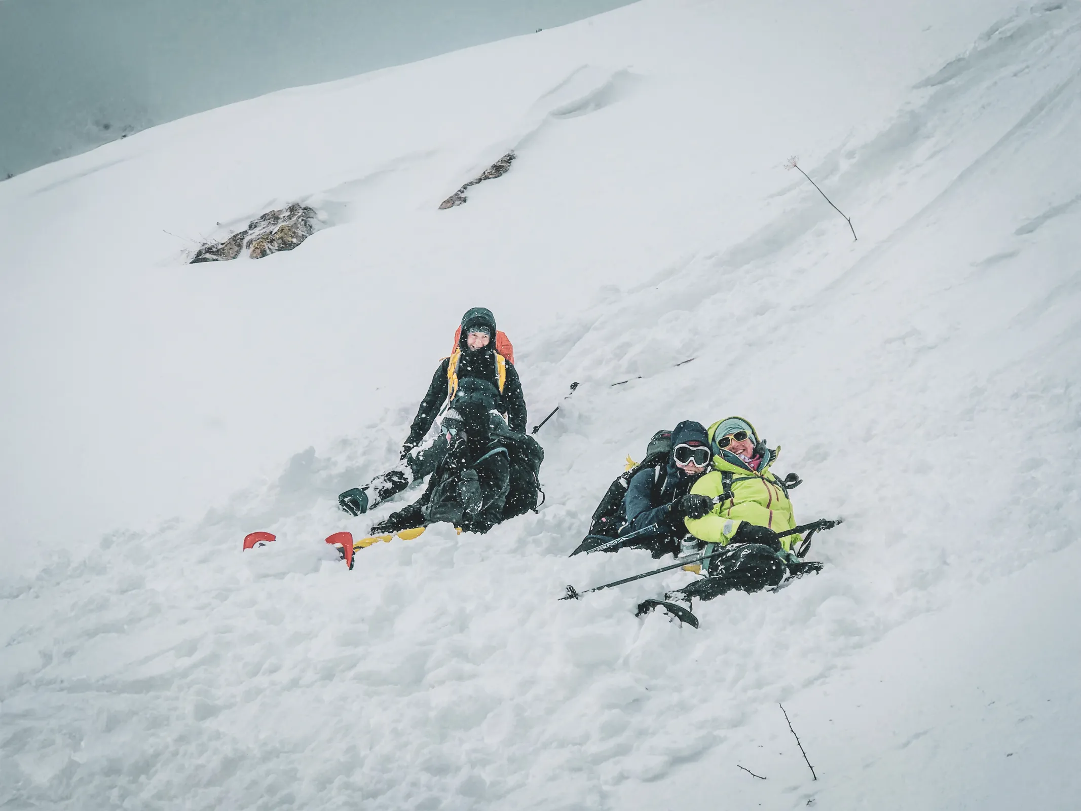 Trois randonneurs en raquettes s'amusent dans la neige face aux majestueux glaciers des Écrins.