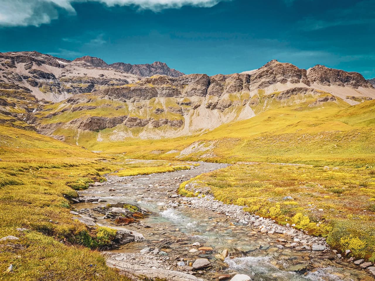 Een adembenemend Alpenlandschap, met majestueuze bergen, weelderige groene weiden en een kristalhelder beekje.