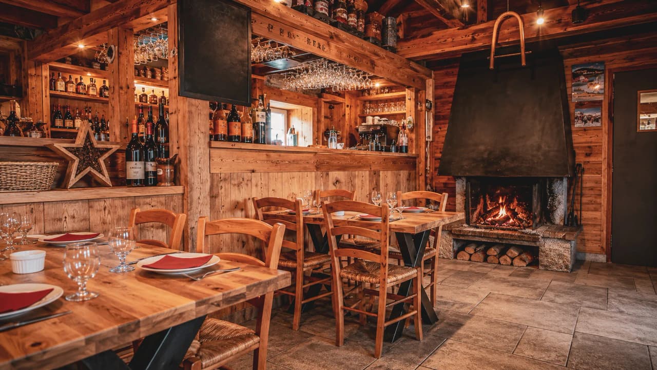 Un chaleureux refuge en bois, avec tables en chêne et cheminée crépitante, parfait après une aventure en montagne.