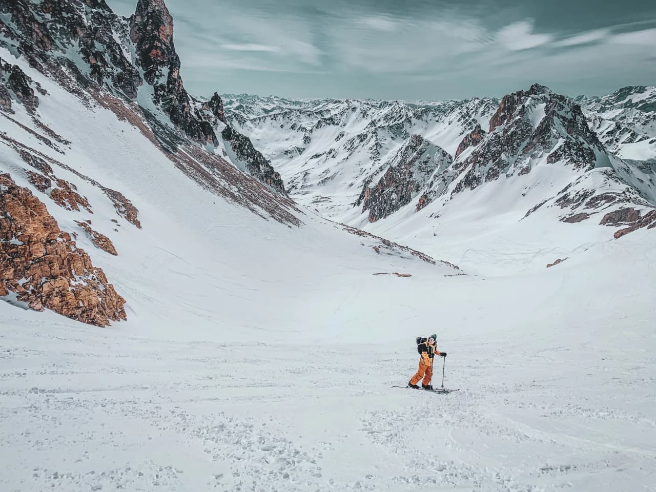 Een eenzame skiër die onder een heldere hemel besneeuwde bergen beklimt: een uitnodiging tot avontuur.