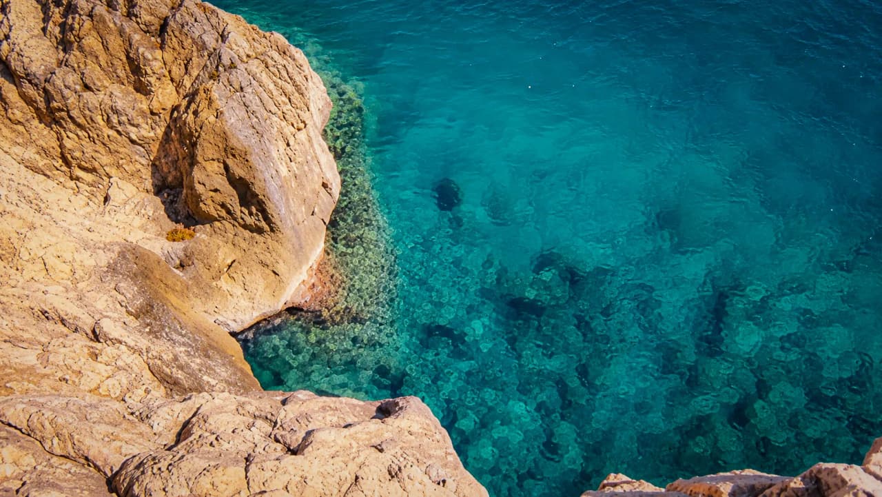 A spectacular view of the Mediterranean, with a sheer cliff and crystal-clear water.