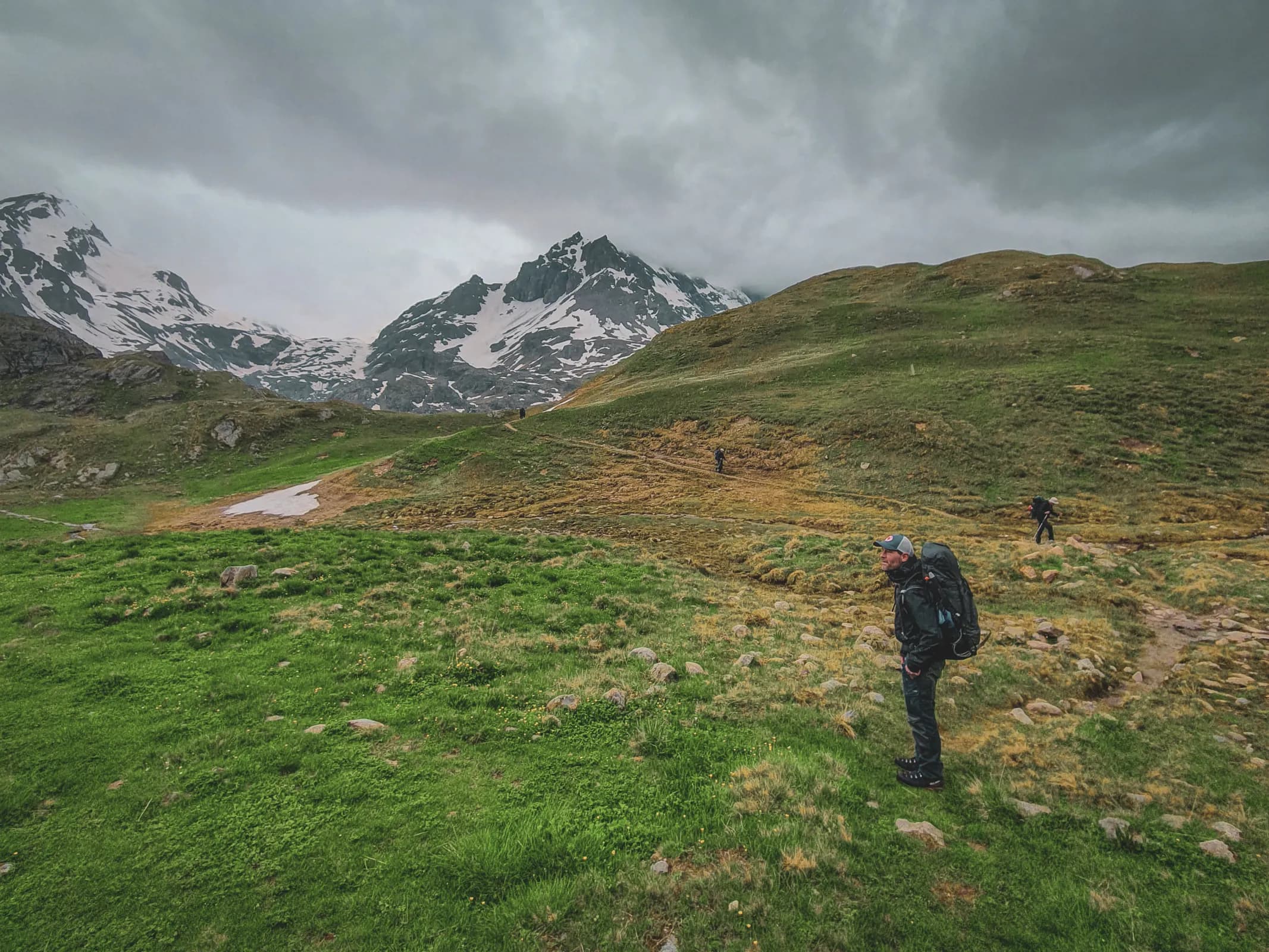 Mountain hiking on the Haute Route, with majestic Alpine peaks and threatening clouds.