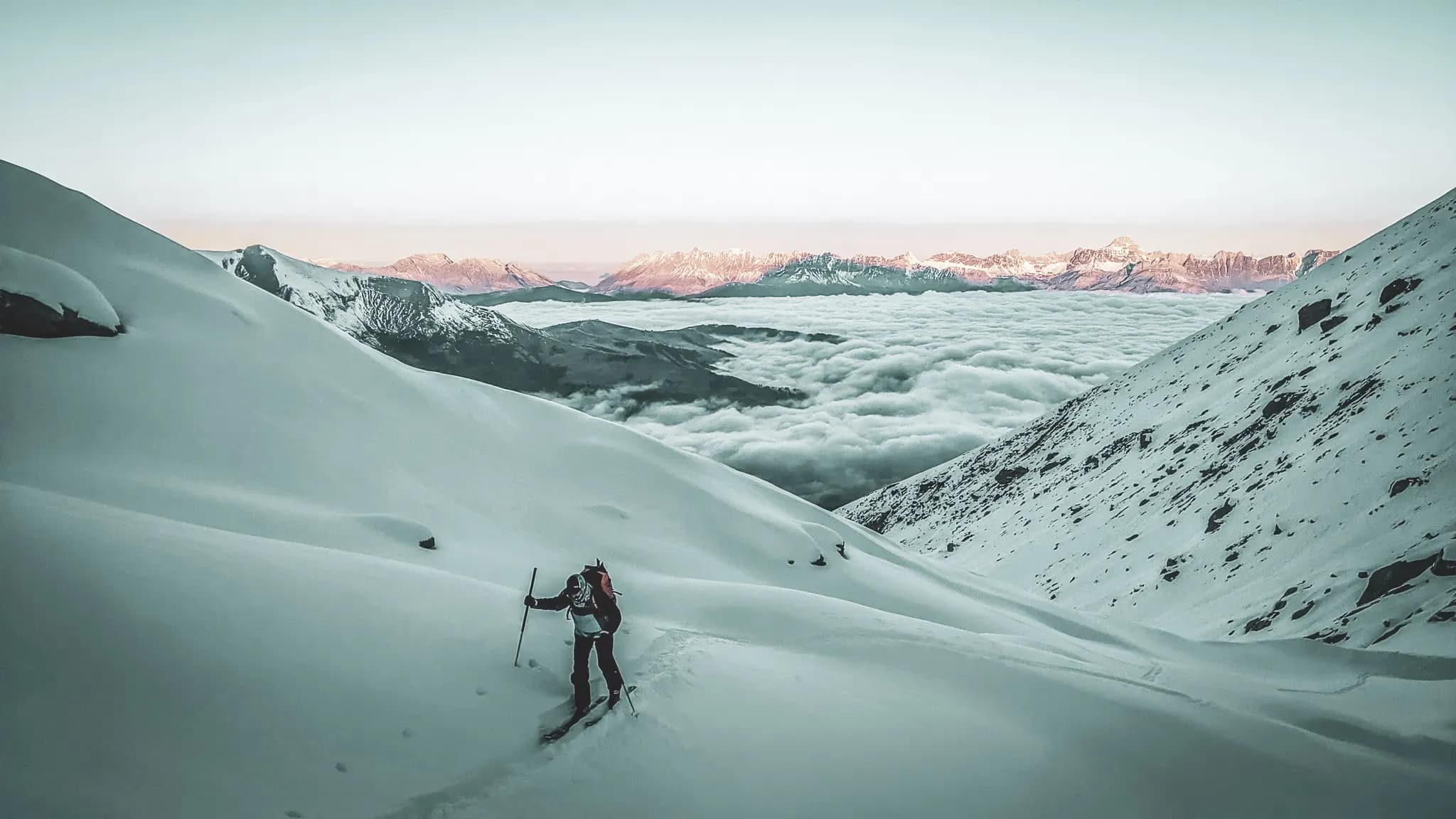 A lone skier explores a majestic snowscape with mountains in the background.