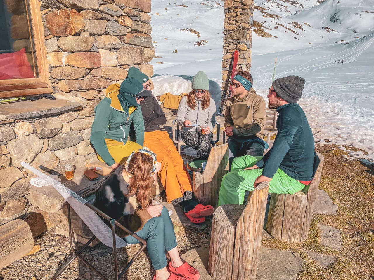 Een groep vrienden die na een wandeling van de zon genieten, omringd door sneeuw en bergen.