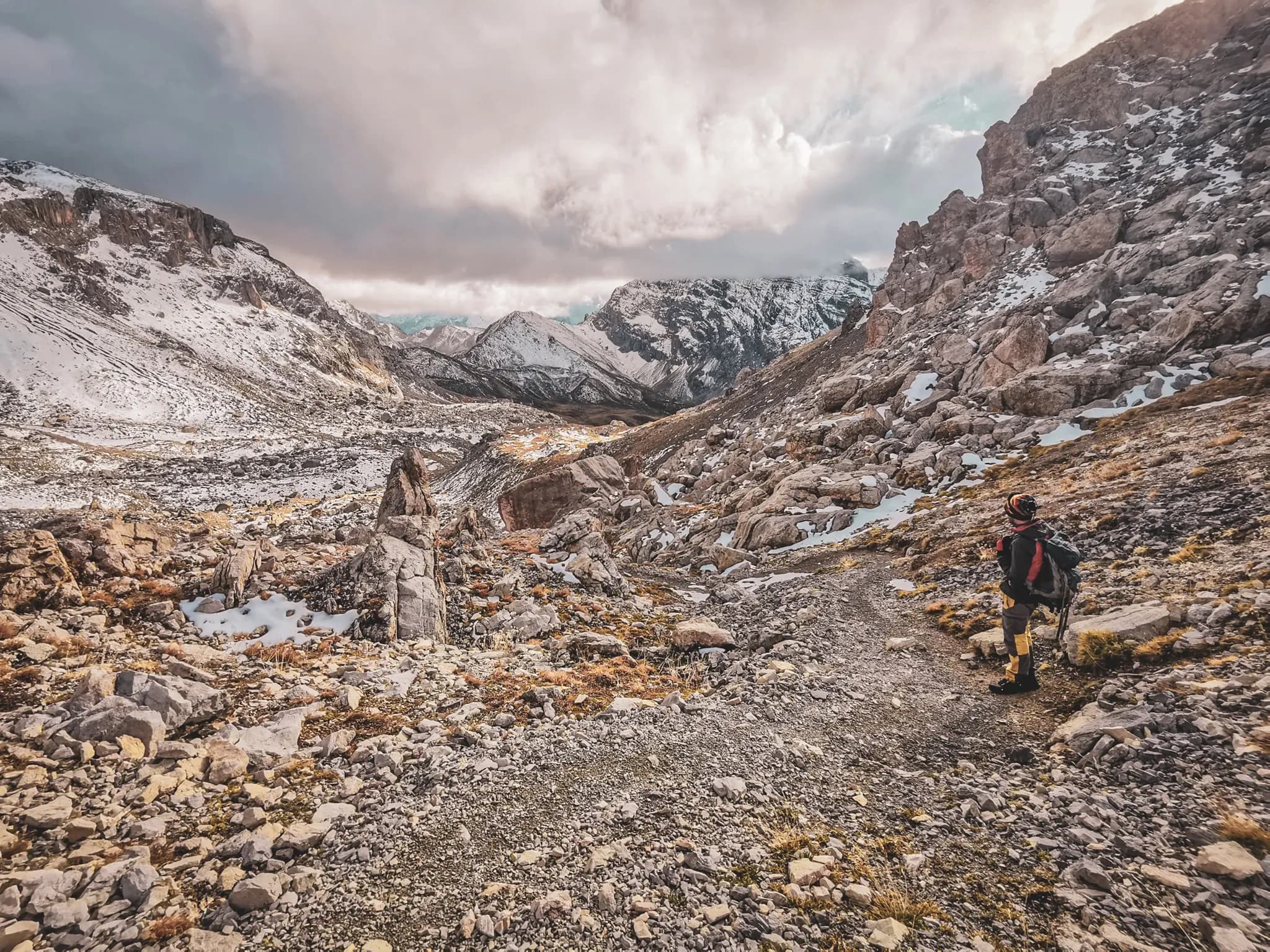 Een wandelaar midden in de Alpen, omringd door majestueuze bergen en wilde landschappen.