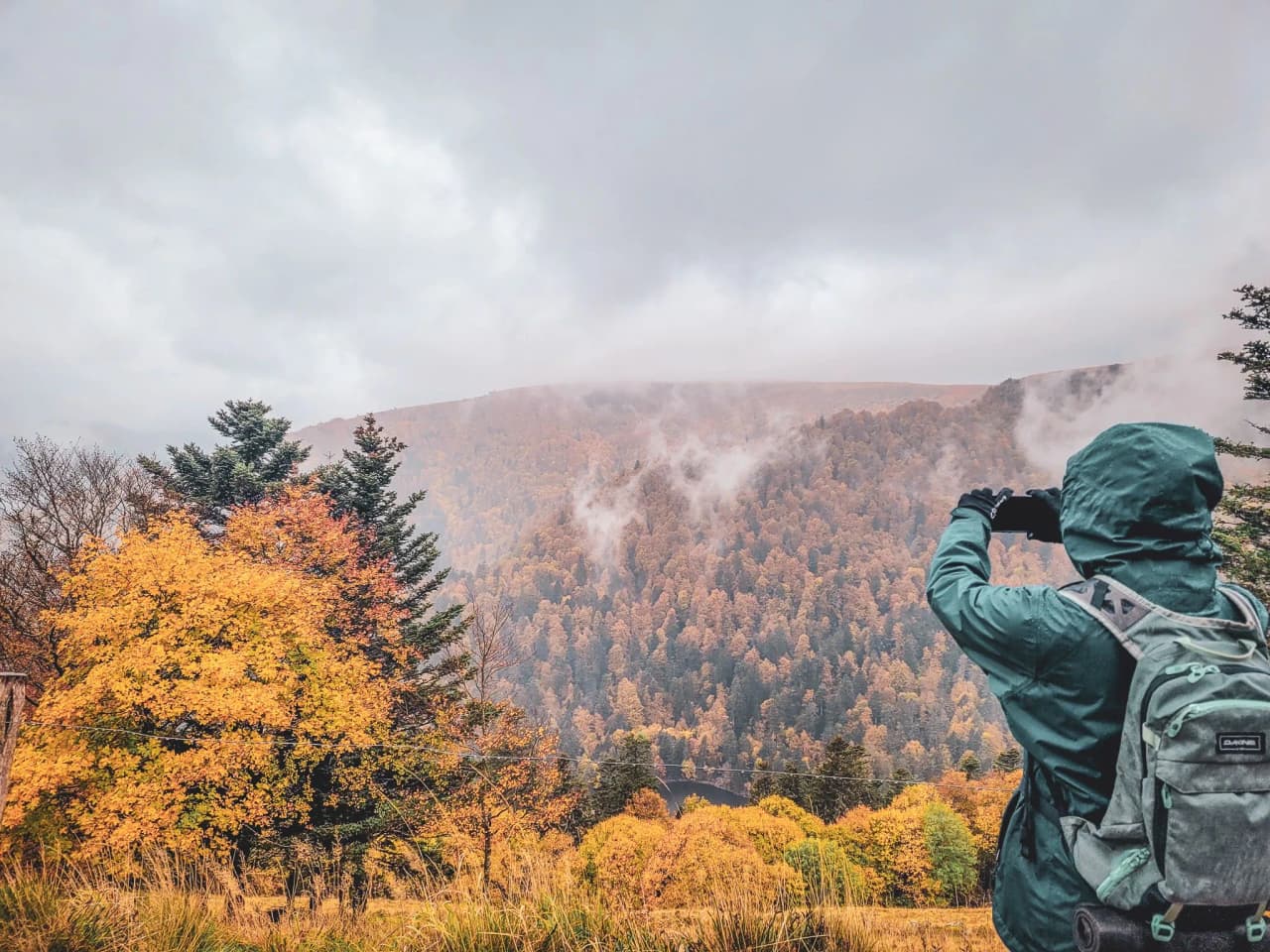 Randonneur admirant les couleurs automnales des Vosges, sous un ciel brumeux et mystérieux.