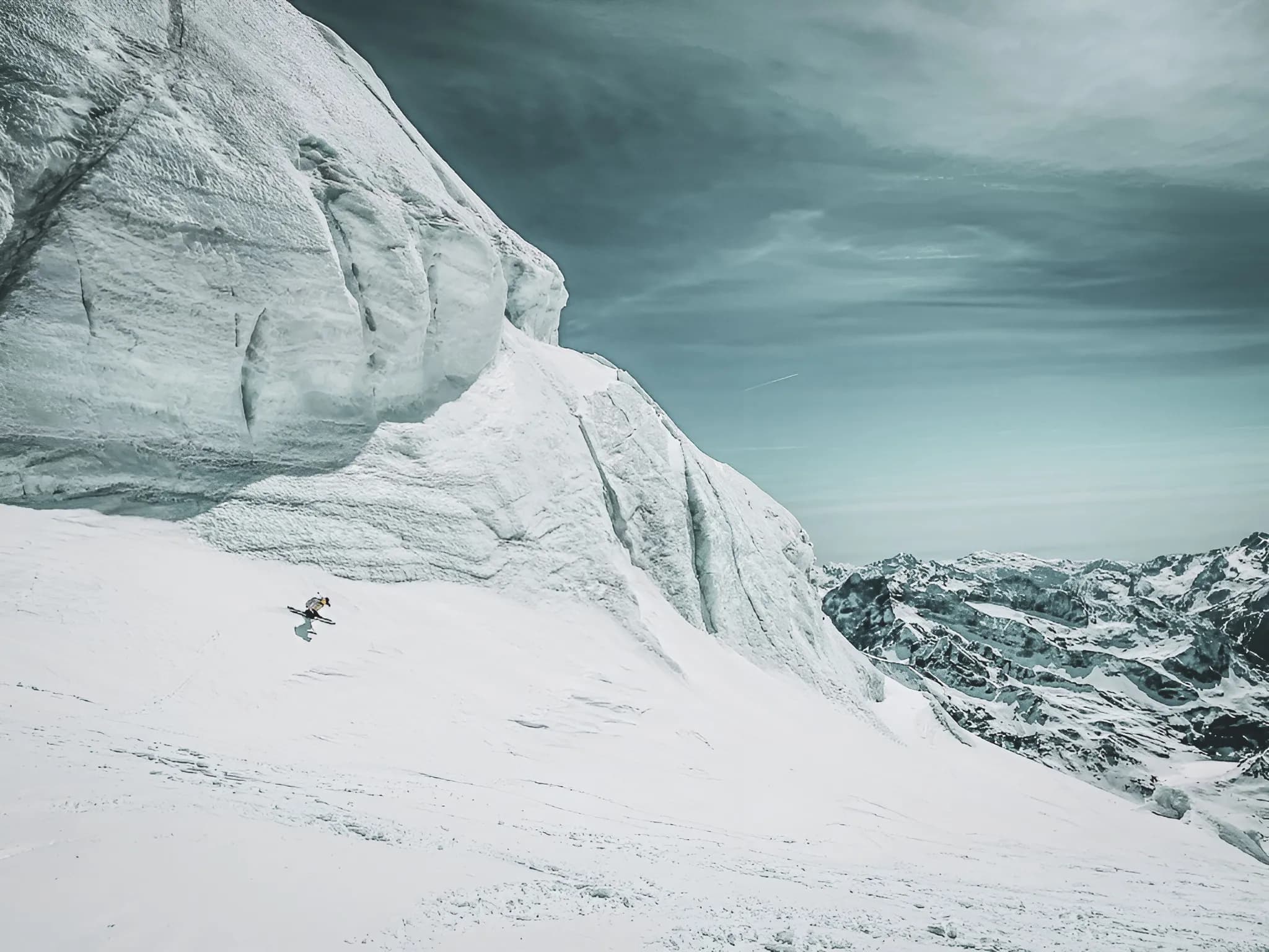 Skieur solitaire descendant une pente enneigée, entouré de majestueux paysages alpins.