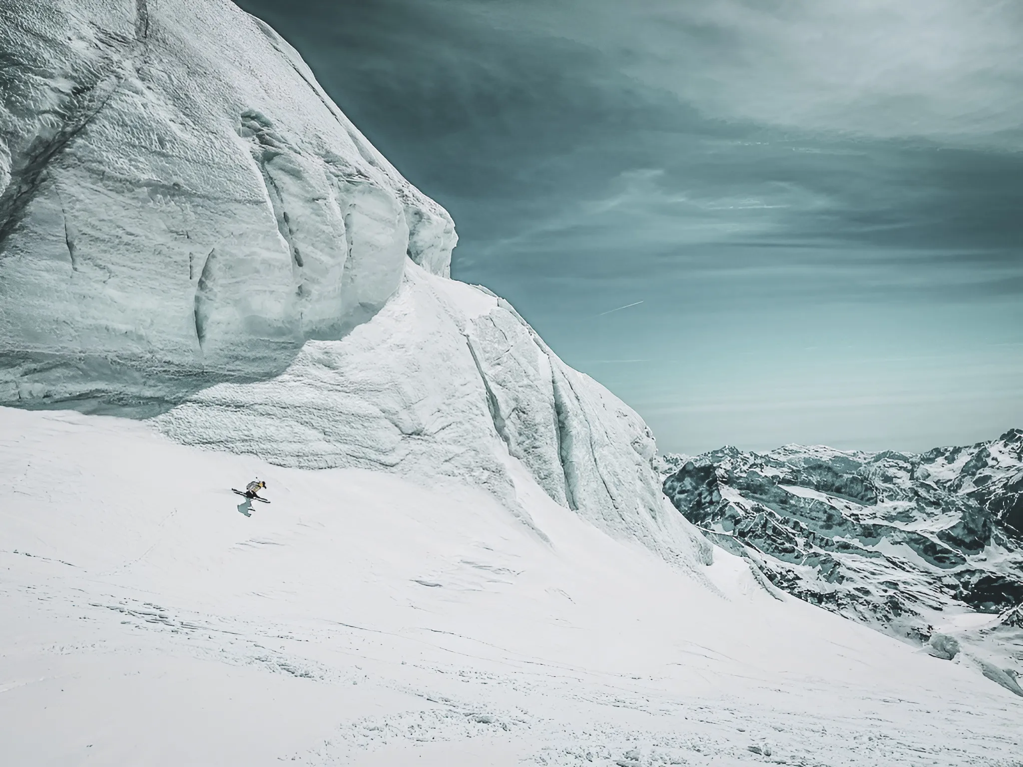 Skieur solitaire descendant une pente enneigée, entouré de majestueux paysages alpins.