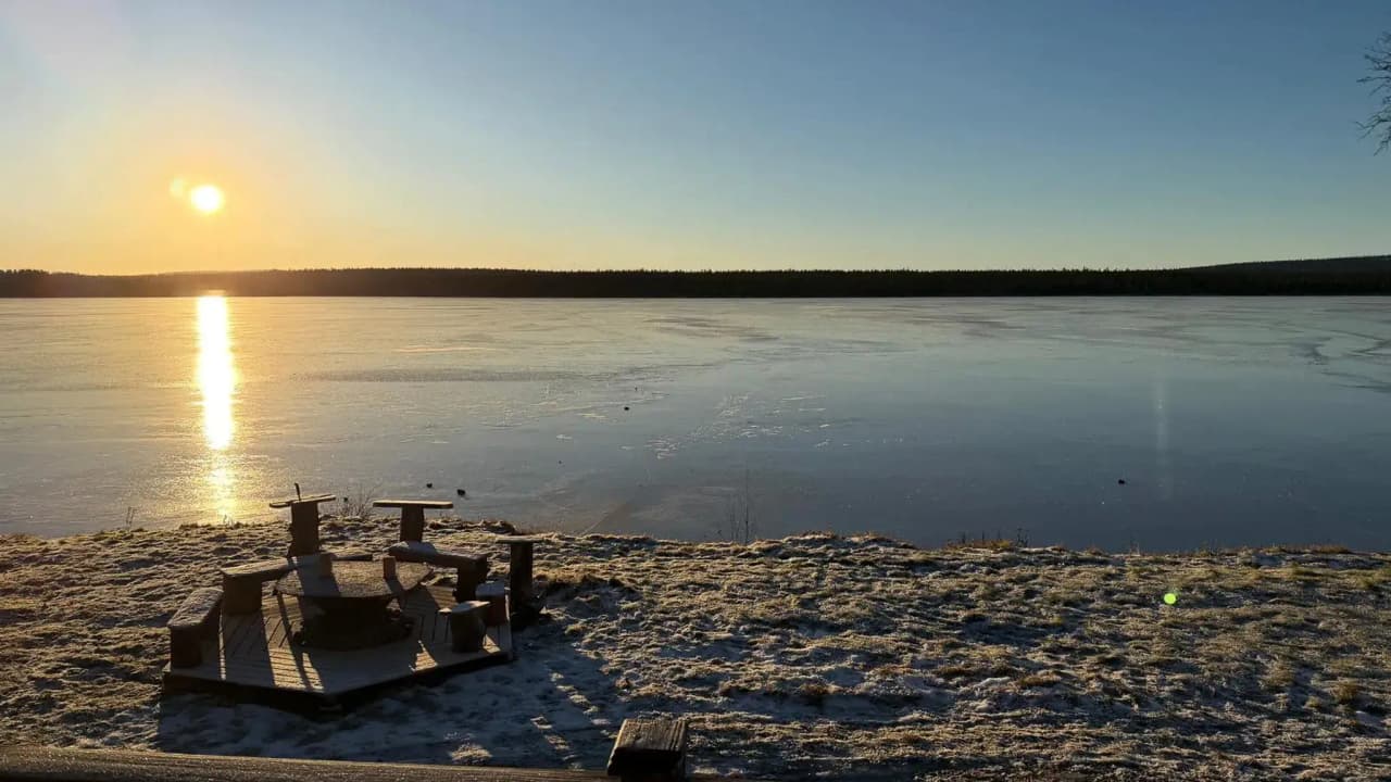 Sunset over a frozen lake in Lapland, offering a peaceful and magical atmosphere.