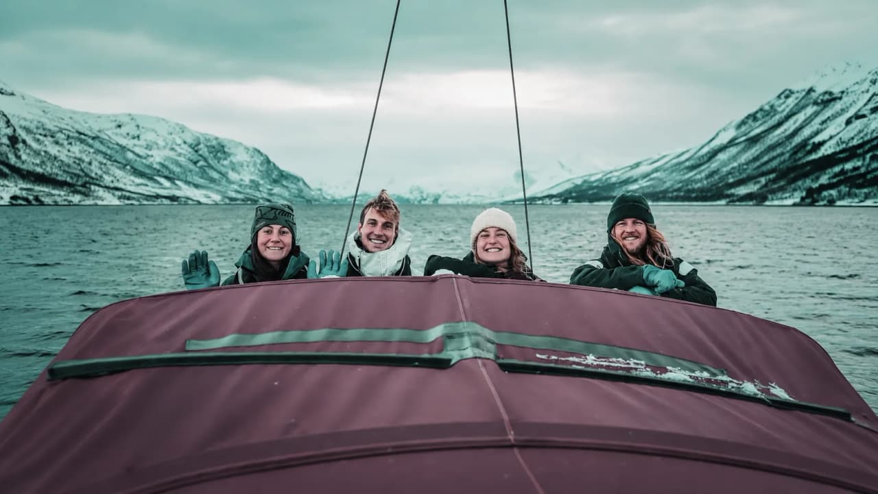 Quatre amis souriants en bateau, entourés de paysages enneigés spectaculaires des Alpes de Lyngen.