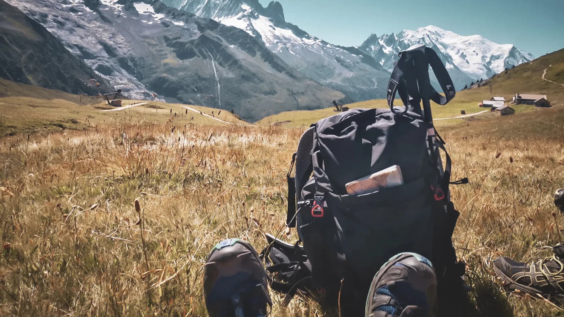 Rucksack on a field of grass, with majestic Alpine peaks in the background.