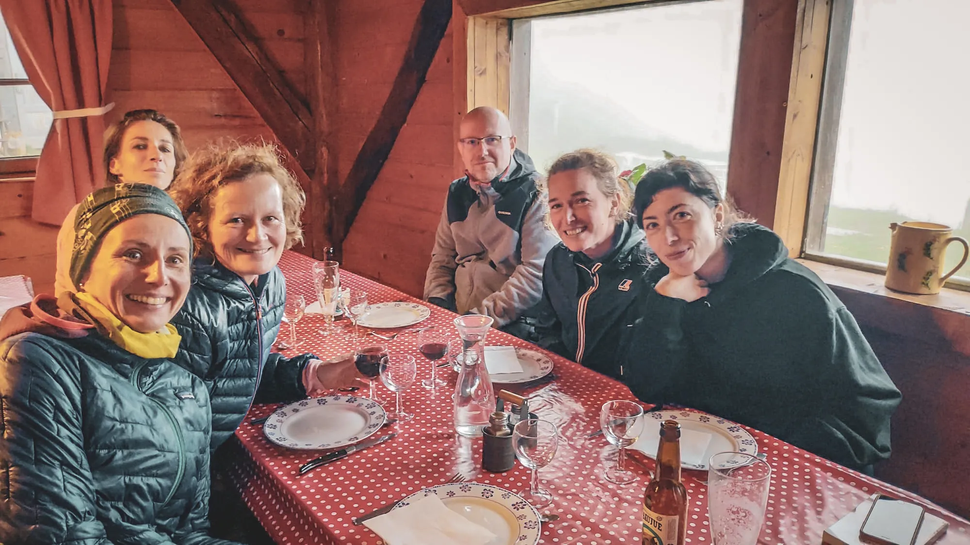 A group of smiling hikers in a cosy Mountain hut, ready to enjoy a mountain meal.