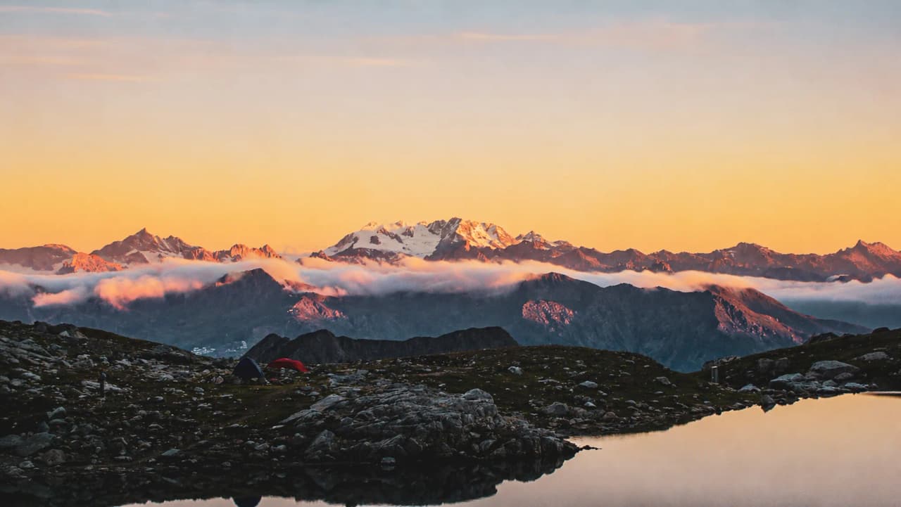 Coucher de soleil sur les montagnes, reflet paisible dans un lac, invitation à l'aventure.