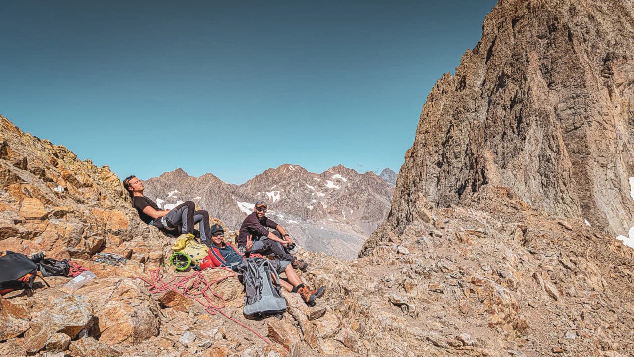 Groupe d'alpinistes se reposant sur des rochers en montagne, avec un panorama époustouflant.