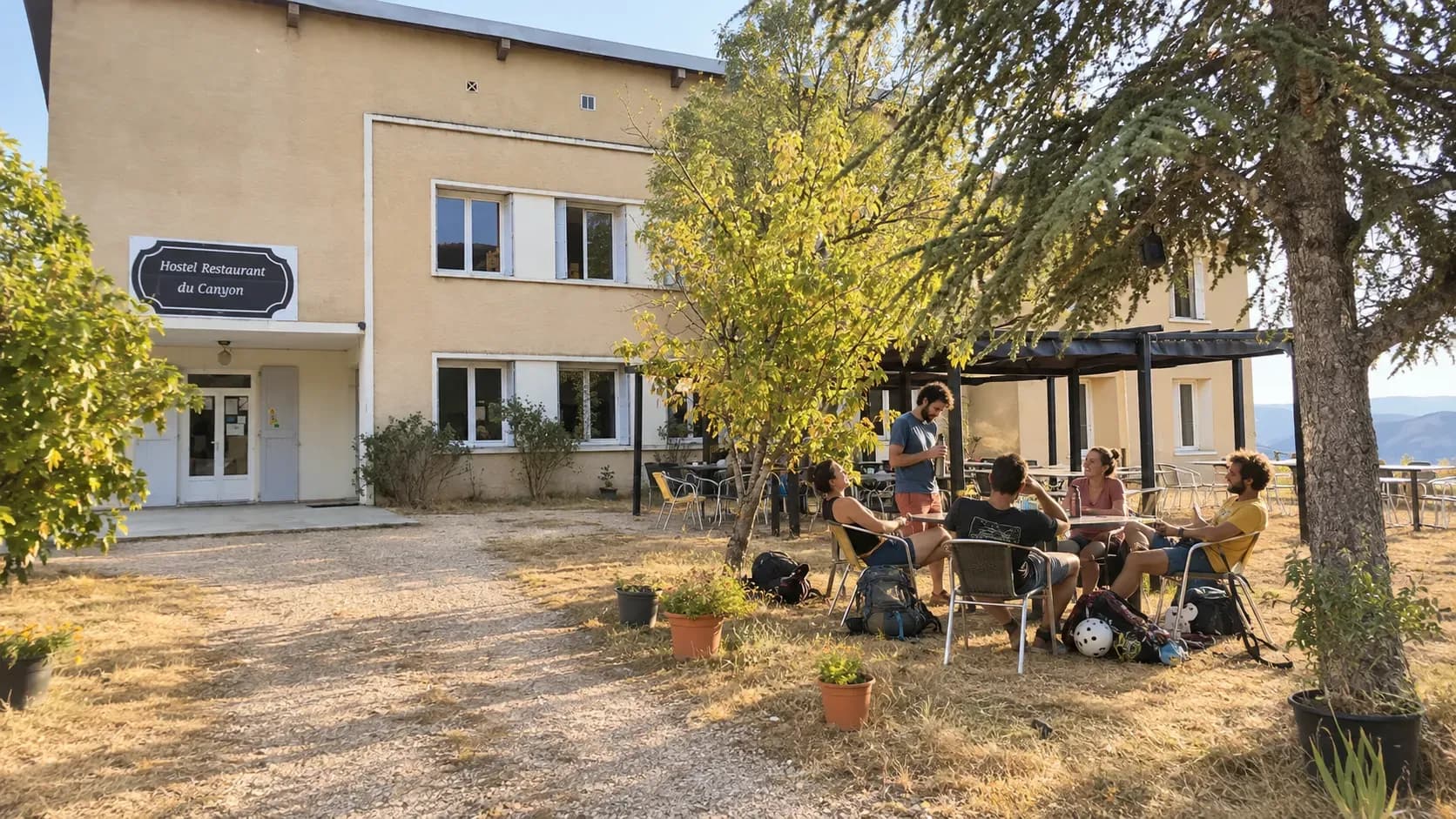 Groupe d'amis se détendant devant l'Auberge du Canyon, entourés de verdure et d'une ambiance conviviale.