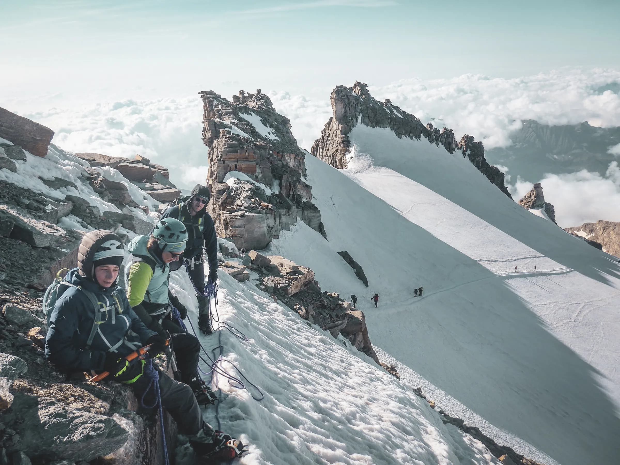 Mountaineering scene in Grand Paradis, climbers on a snow-capped peak surrounded by clouds.