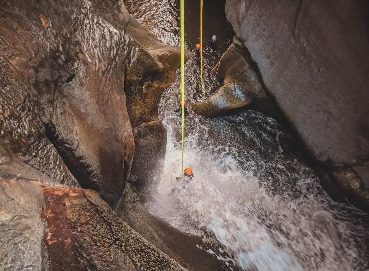 Aventure en canyoning : chutes d'eau cristallines et rochers spectaculaires dans les Pyrénées.