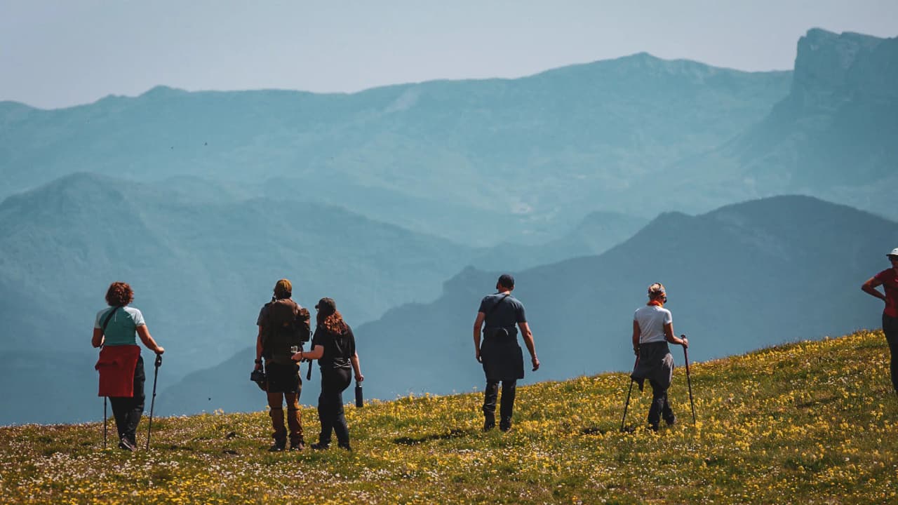 A group of hikers on a Vercors summit, facing a spectacular sunset.
