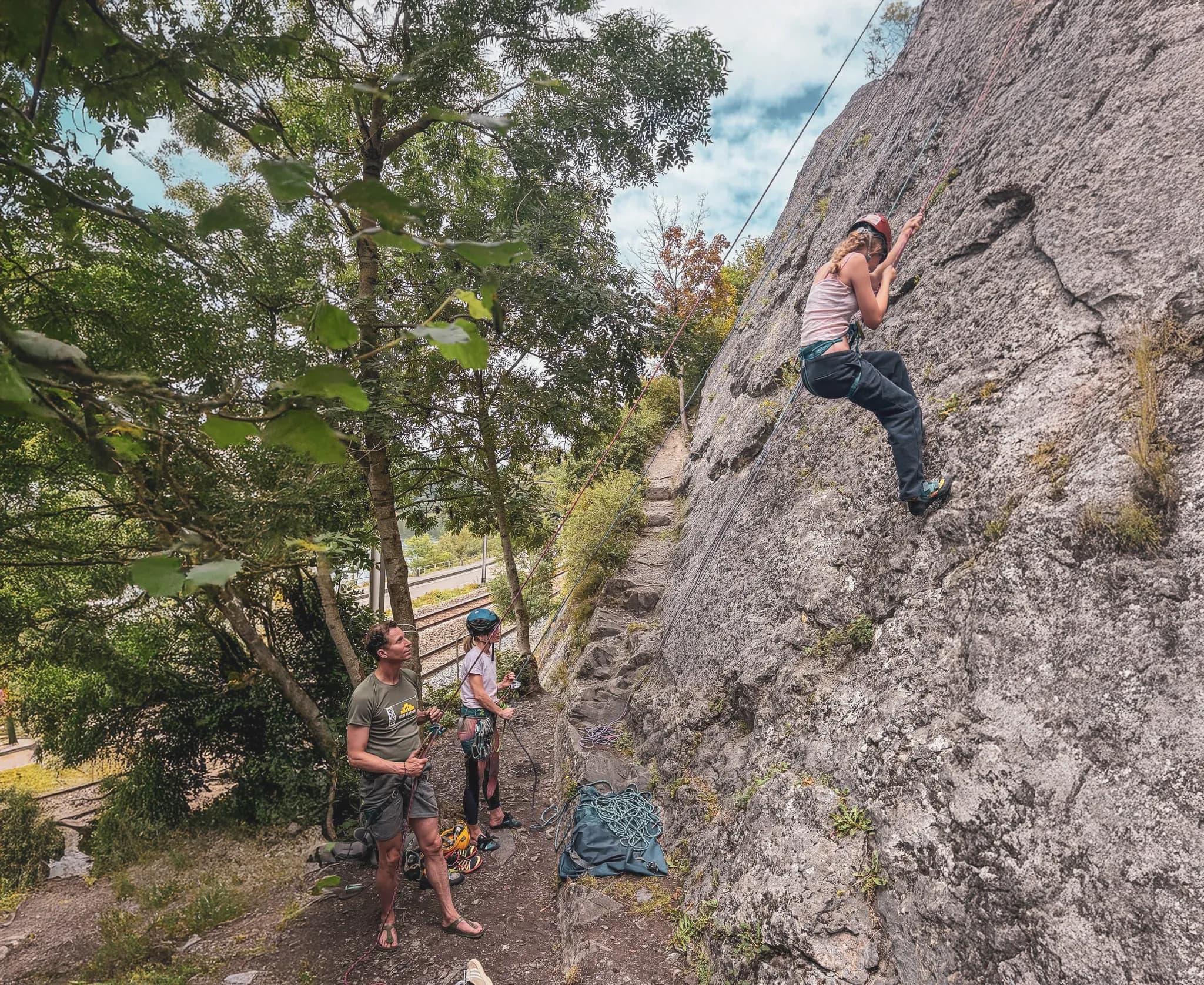 A climber takes up climbing on a green cliff surrounded by nature.