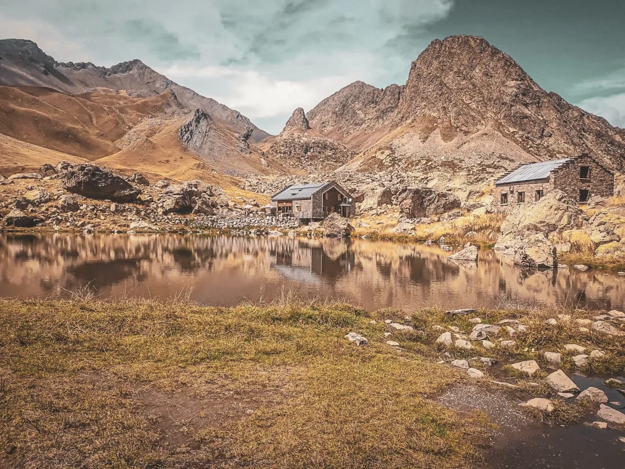 Refuge pittoresque au bord d'un lac, entouré de montagnes majestueuses et de paysages sauvages.