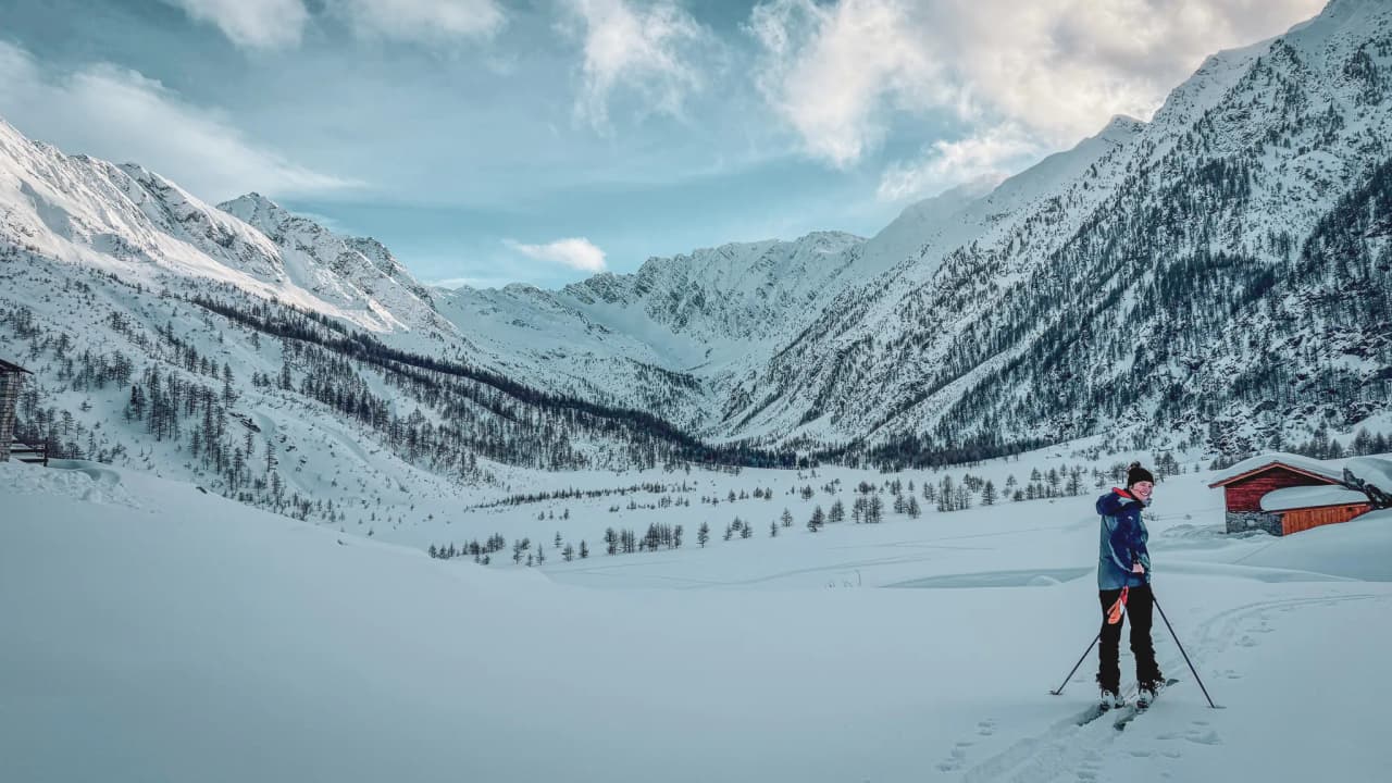 A smiling skier explores a majestic snow-covered landscape in the Italian Alps.