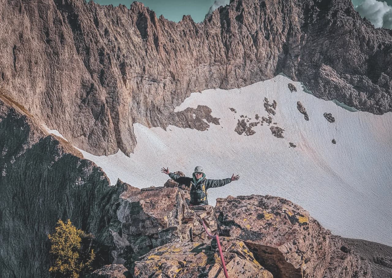 Happy climber at the top of a snow-covered mountain peak in the Ecrins mountains