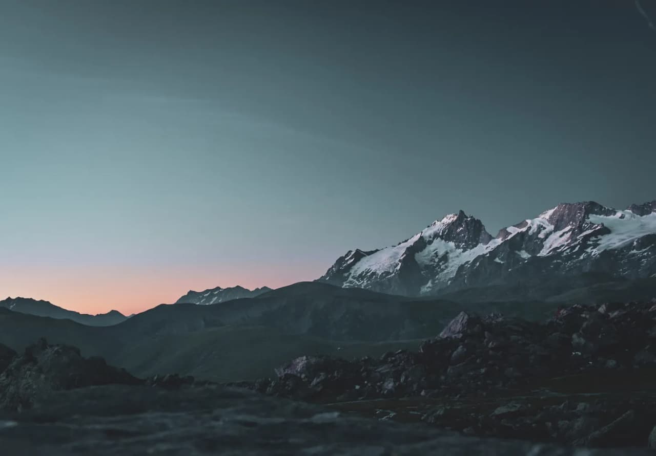 Een spectaculair uitzicht op de besneeuwde bergen bij zonsopgang, dat uitnodigt tot avontuur en verwondering.