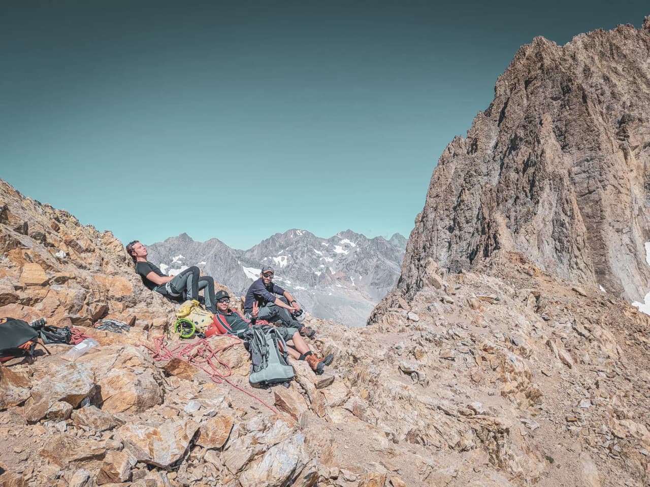 A group of climbers resting on sun-drenched rocks in a breathtaking mountain setting.