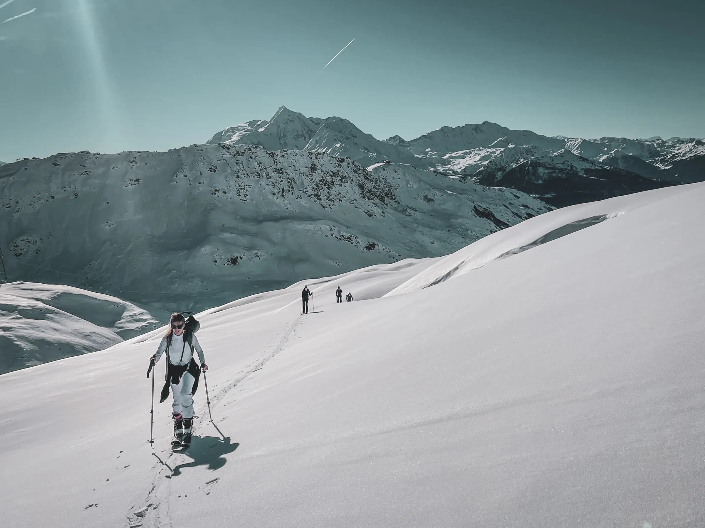 Hikers on dazzling glaciers, surrounded by majestic mountains.