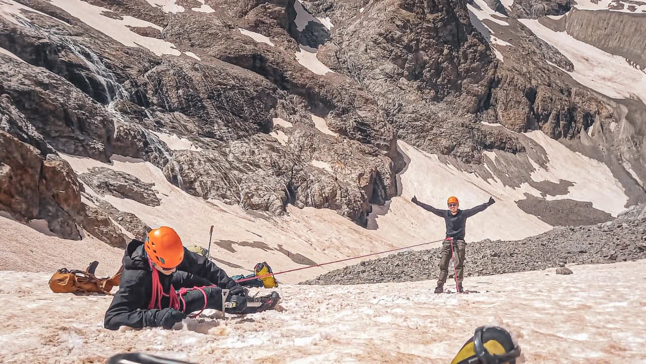 Deux alpinistes en pleine action dans les Écrins, sous un ciel radieux, découvrent les sommets.