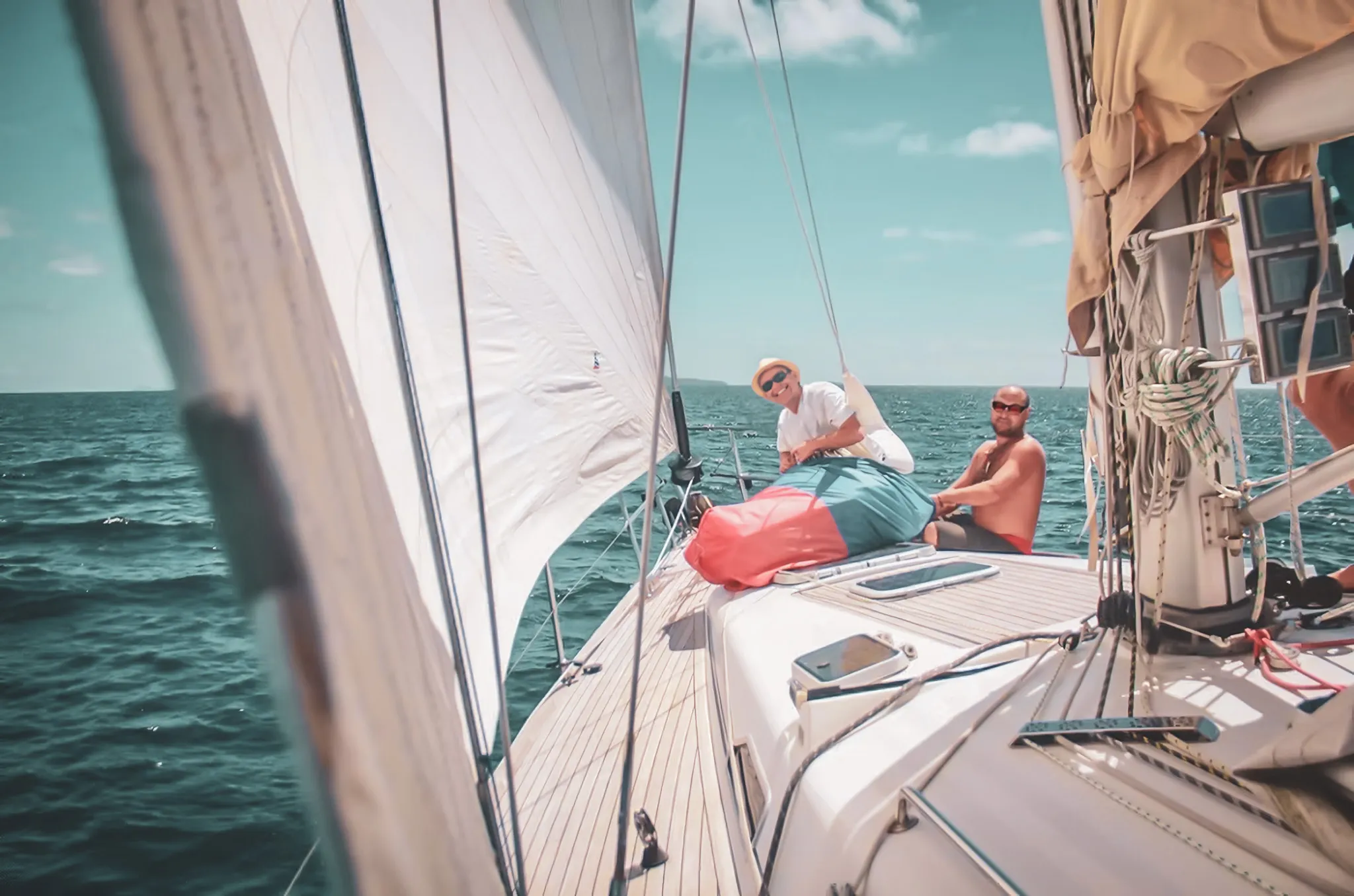 À bord d'un voilier, des voyageurs profitent de l'océan turquoise sous le soleil radieux.