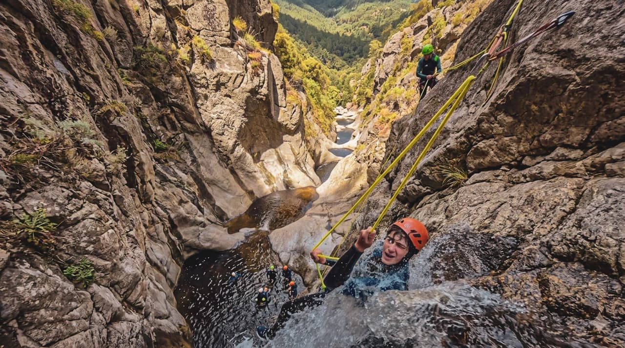Aventure en canyoning : un participant glisse sur l'eau, entouré de falaises et d'un paysage verdoyant.