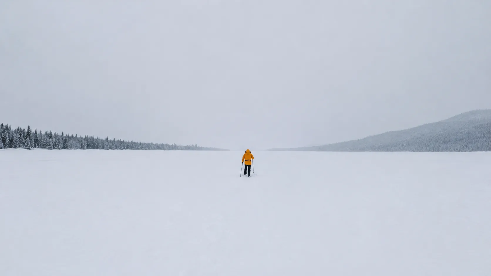 Een avonturier in een gele jumpsuit doorkruist een besneeuwd landschap, omringd door majestueuze dennenbomen.