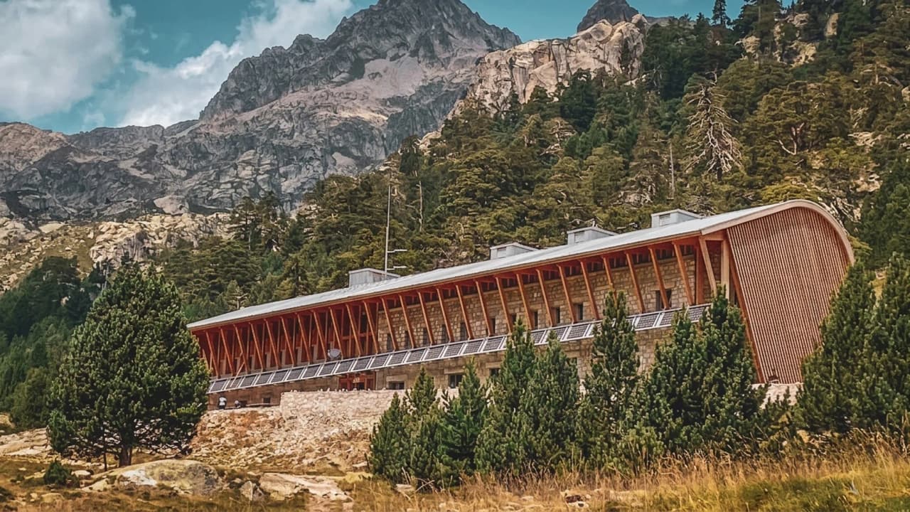 A modern Mountain hut nestled between majestic mountains, surrounded by greenery and adventure.