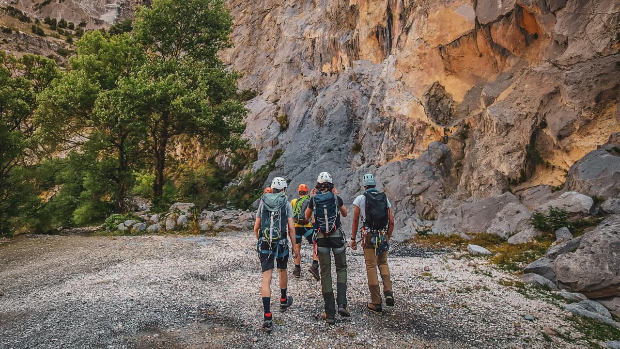 Groupe d'aventuriers marchant vers des falaises majestueuses, prêt pour l'escalade en montagne.