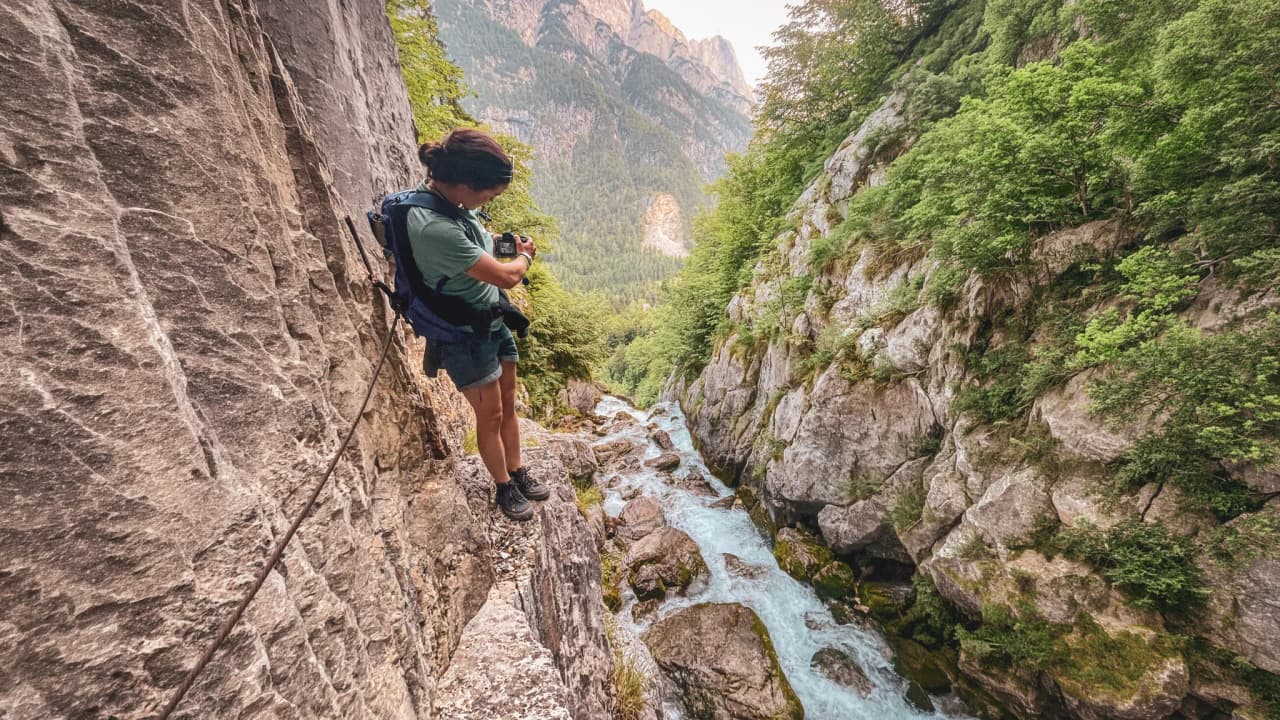 Adventurer on a steep path, capturing the beauty of Slovenia's alpine rivers.