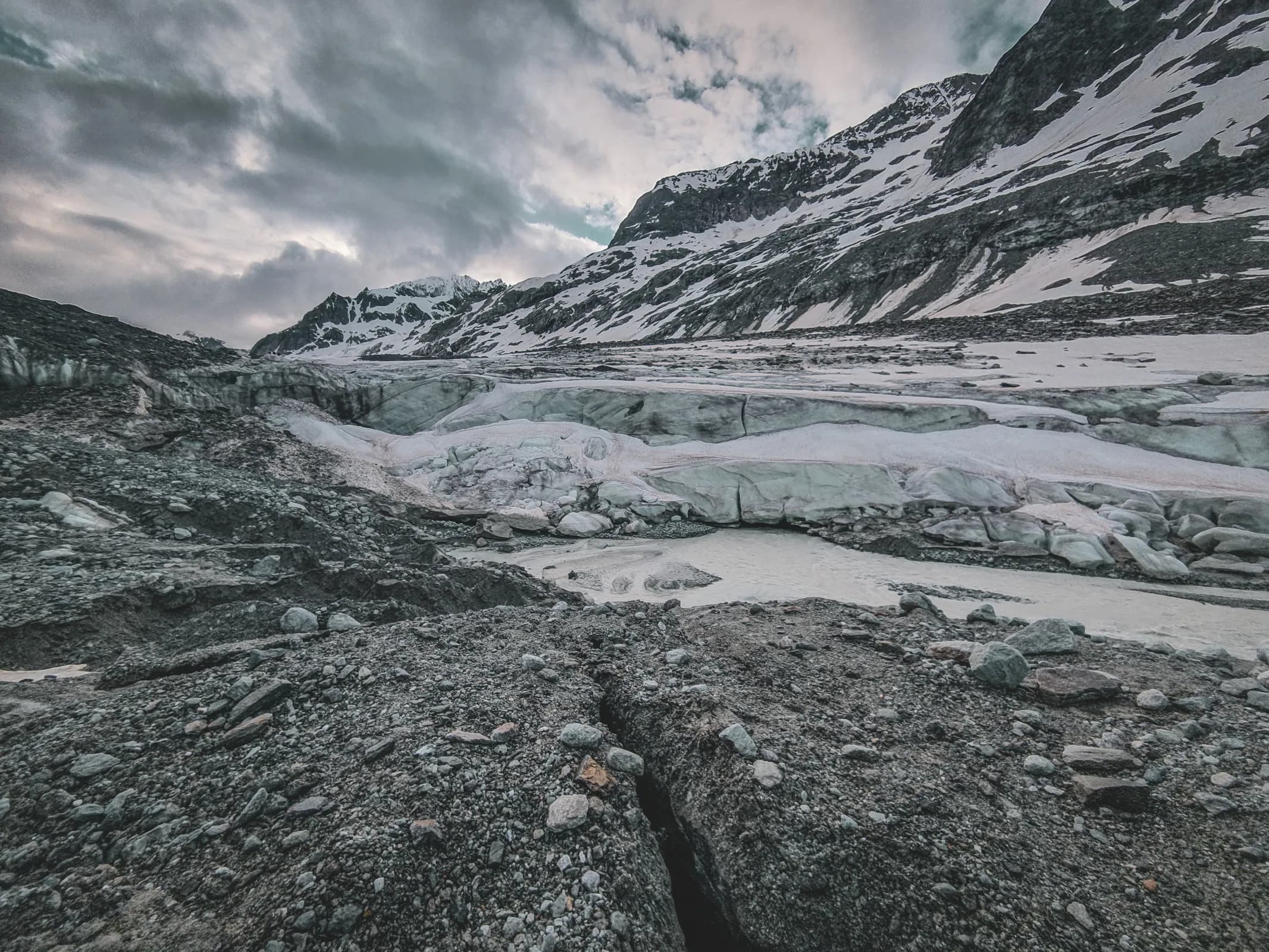 A spectacular glacial landscape between Alpine peaks, combining snow and dark rock.