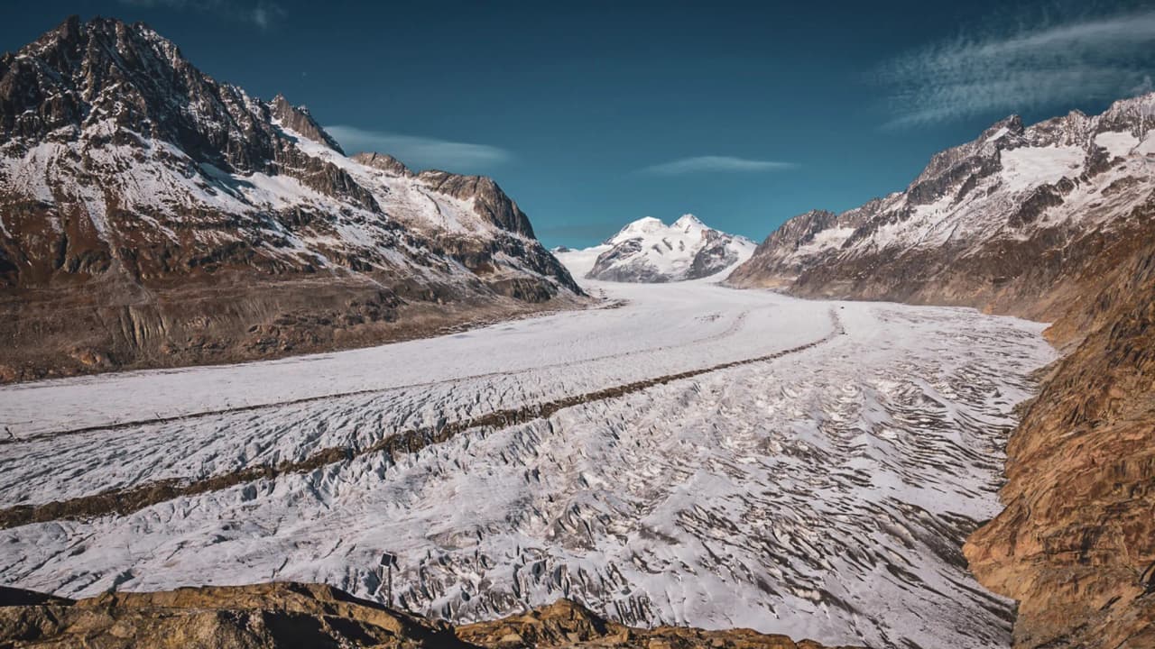 Panorama spectaculaire du glacier d'Aletsch, entre montagnes majestueuses et ciel bleu.