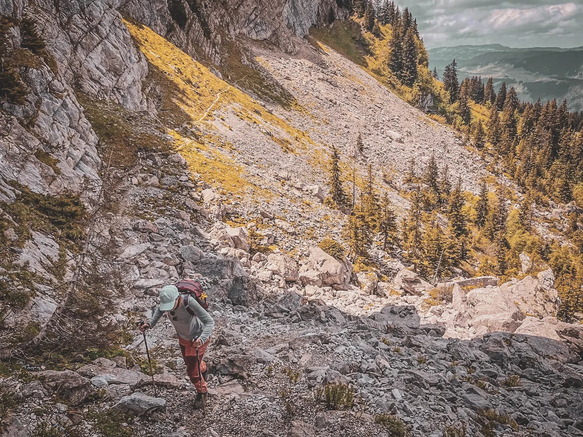 randonneur grimpant un sentier rocheux sous les majestueuses Aravis.