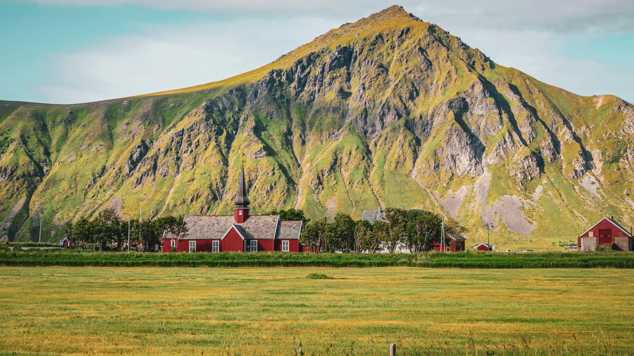 Magnificent landscape of the Lofoten Islands, with green mountains and a picturesque red church.