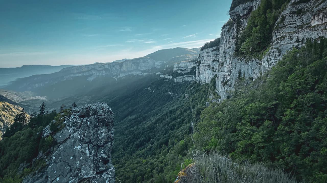 A hiker exploring the mountainous landscapes of the Vercors, between green meadows and summits.