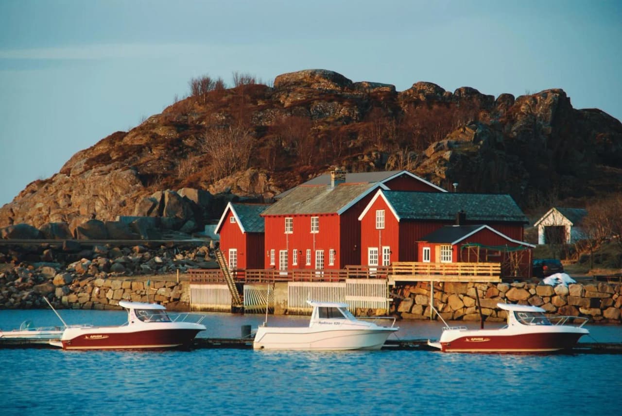 Charming Lofoten landscape with picturesque red houses and boats on the calm water.