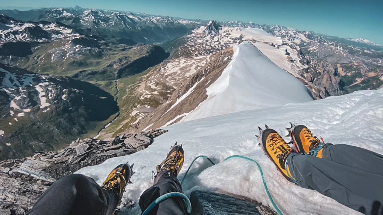 Vue impressionnante depuis un sommet enneigé, avec des crampons et des chaînes de montagne en arrière-plan.