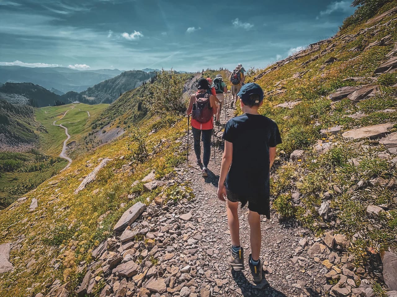 A mountain hike with views of a lush Alpine landscape under a brilliant blue sky.