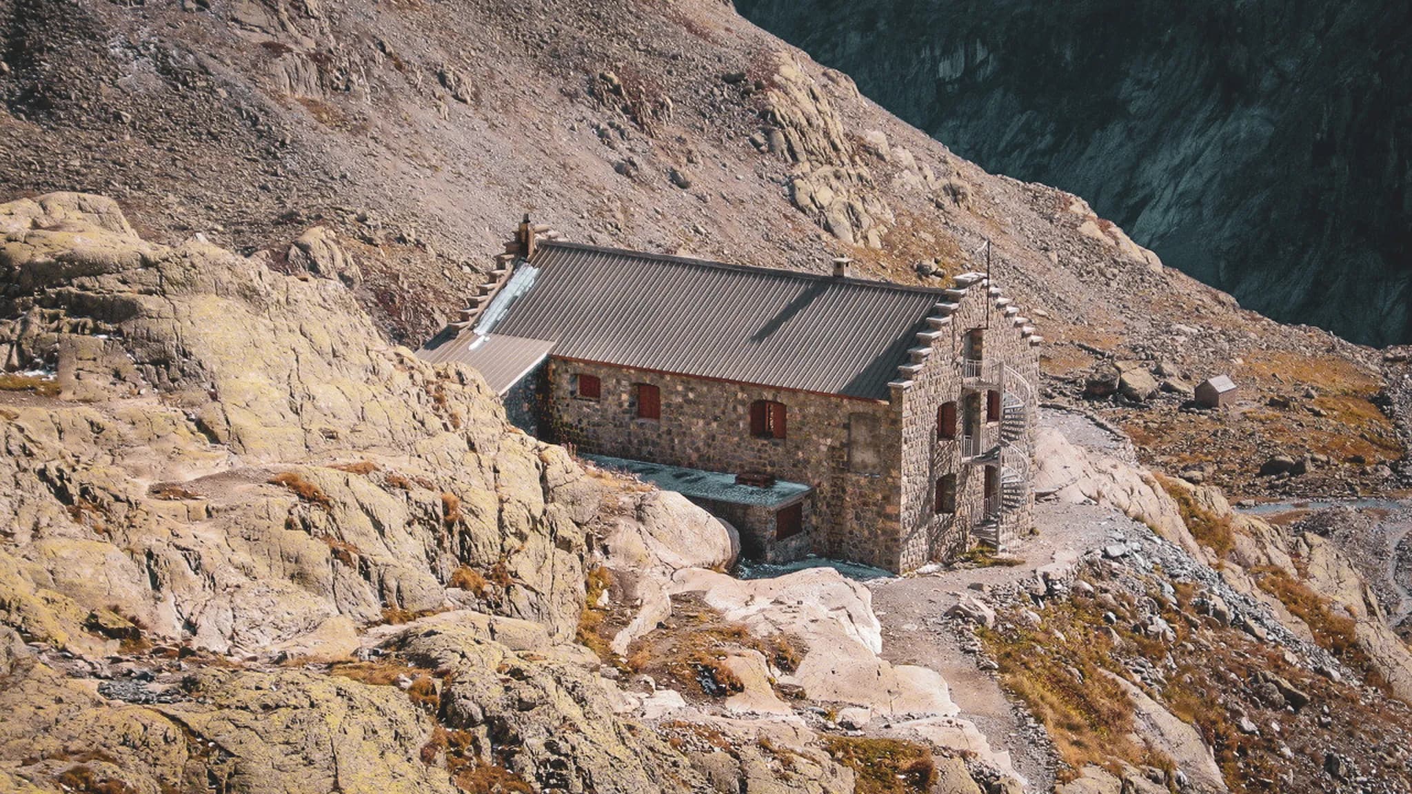 Refuge en pierre au cœur des Écrins, entouré de rochers et de paysages alpins à couper le souffle.