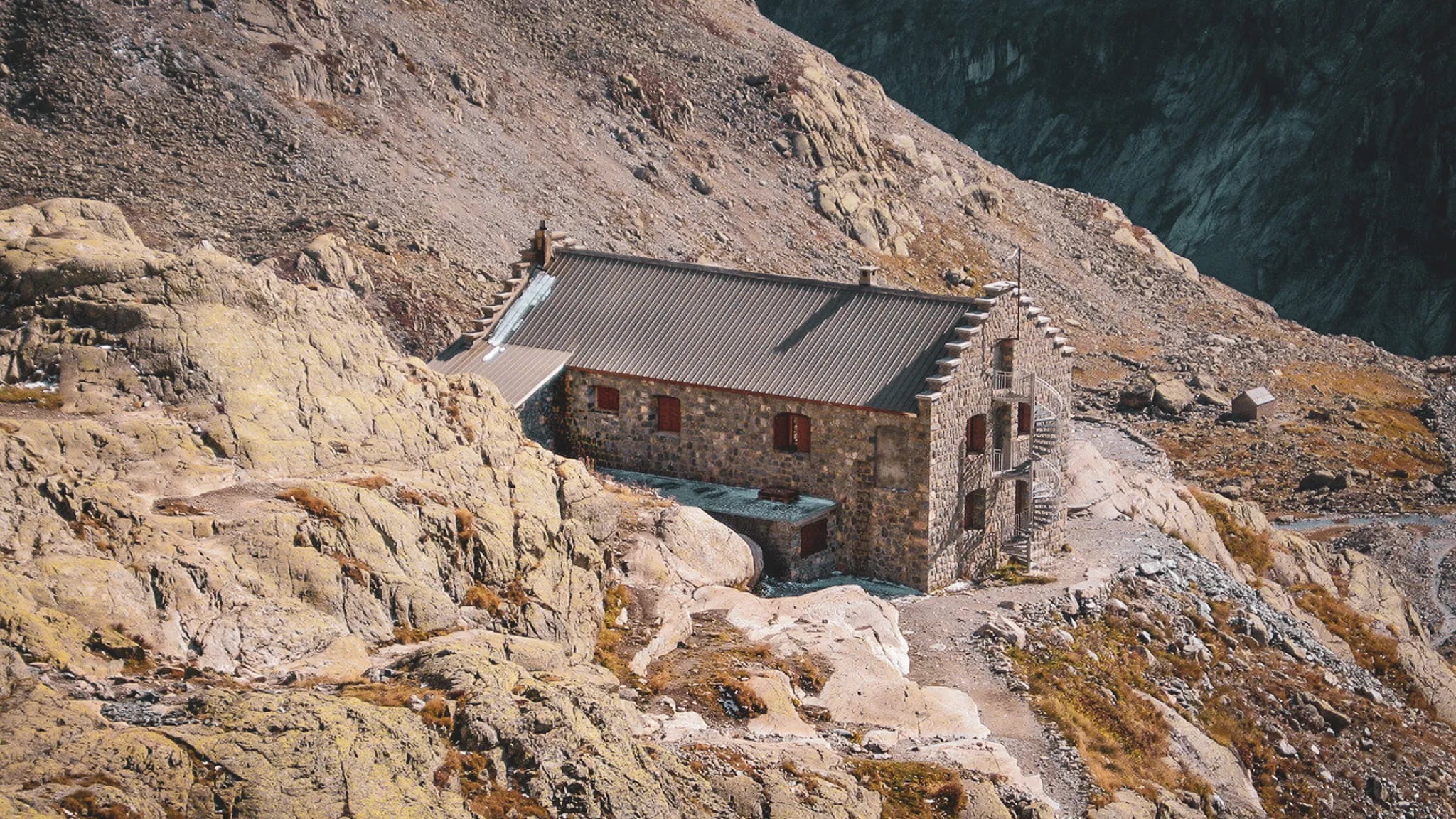 Refuge en pierre au cœur des Écrins, entouré de rochers et de paysages alpins à couper le souffle.