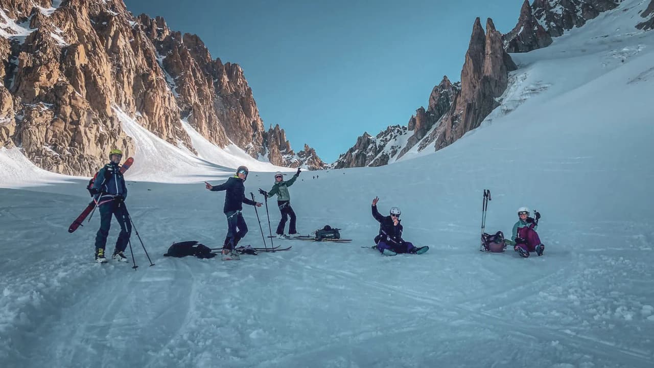 Skiers crossing glaciers under azure skies, surrounded by majestic mountains.