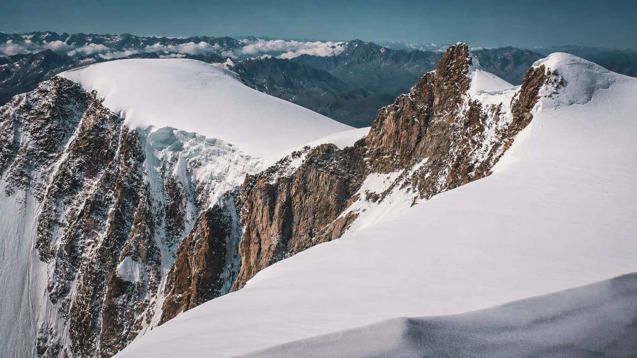Een dorre berglandschap onder een blauwe hemel, ongerepte gletsjers en majestueuze bergtoppen nodigen uit tot avontuur.